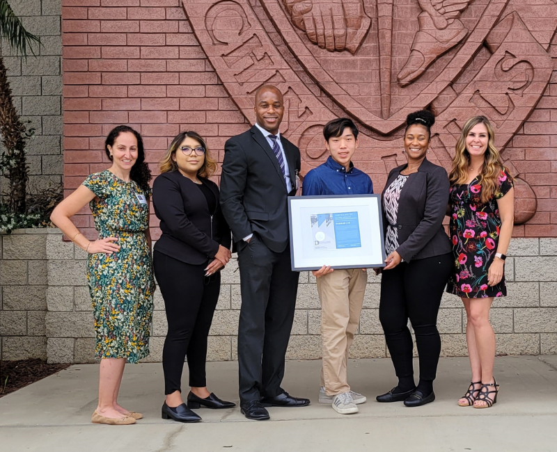 D'Andre Lampkin presenting Lampkin Foundation scholarship award to a high school senior pursuing higher education in community resilience
