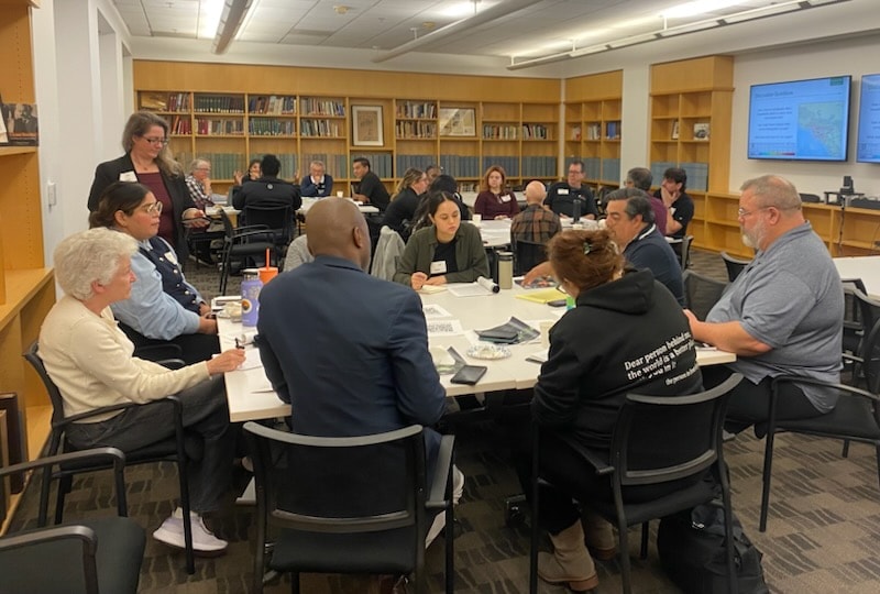 Community leaders and emergency management officials collaborating at disaster recovery planning session in library