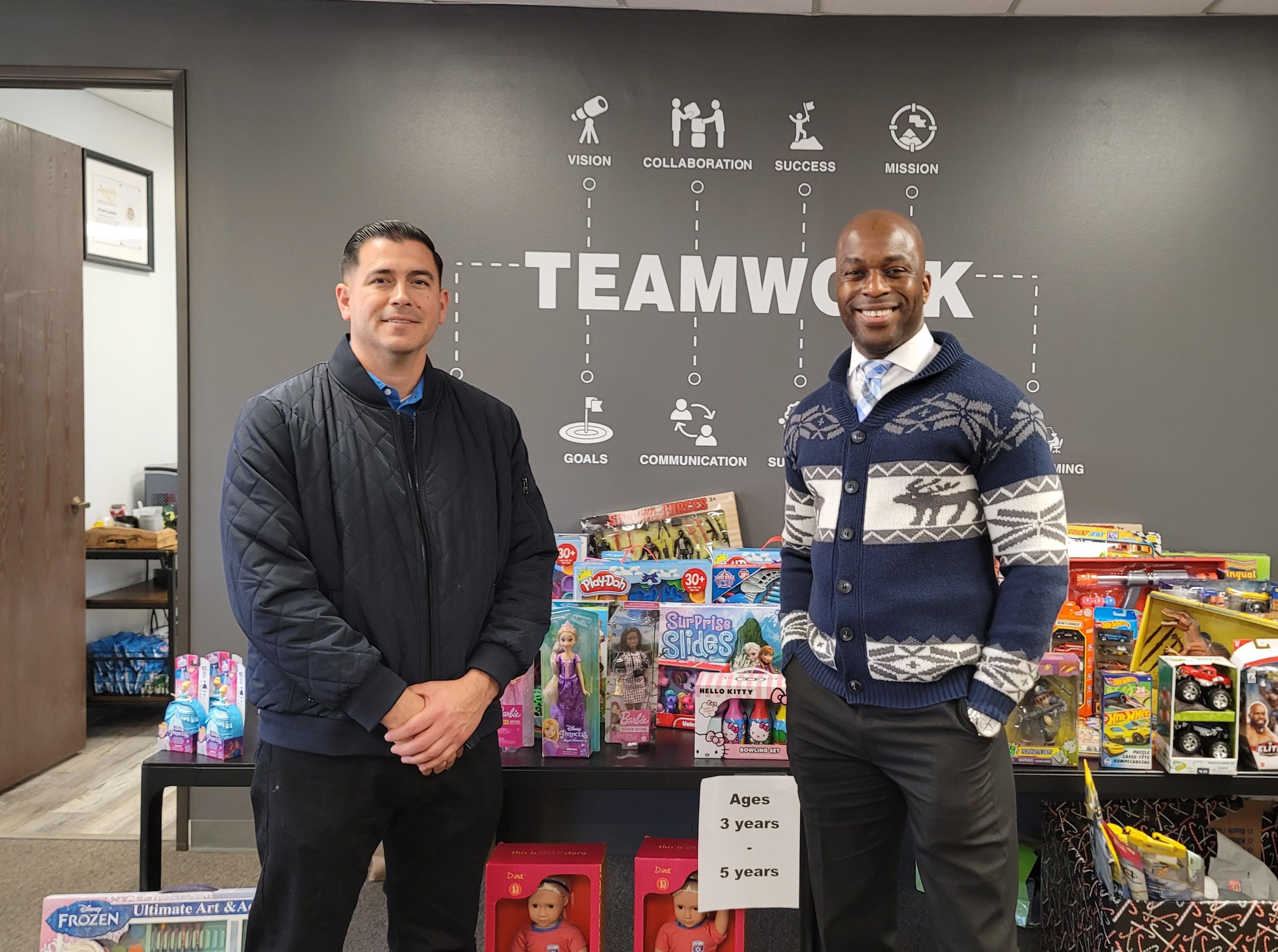 D'Andre Lampkin and colleague at Lampkin Foundation office toy drive in front of Teamwork mural